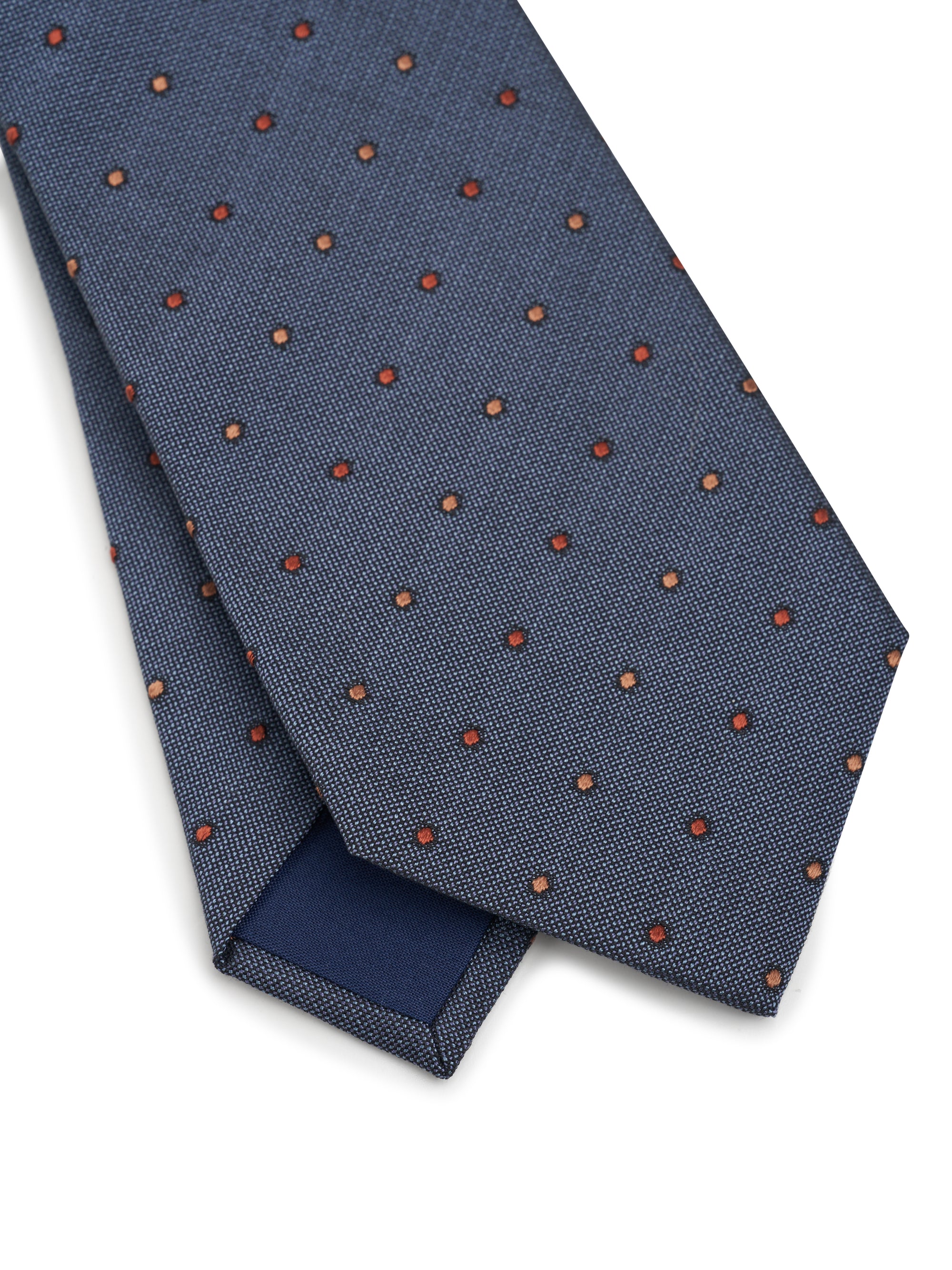 Folded blue tie with red polka dots on a white background