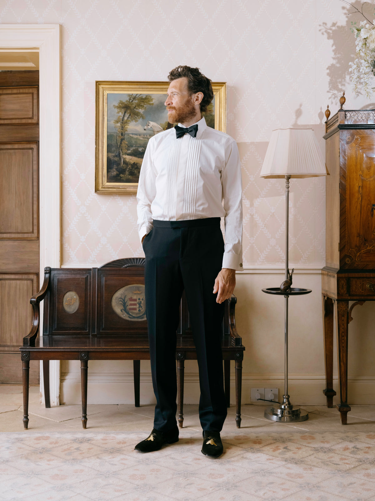 A white pleated evening shirt worn with a black bow tie and dress trousers