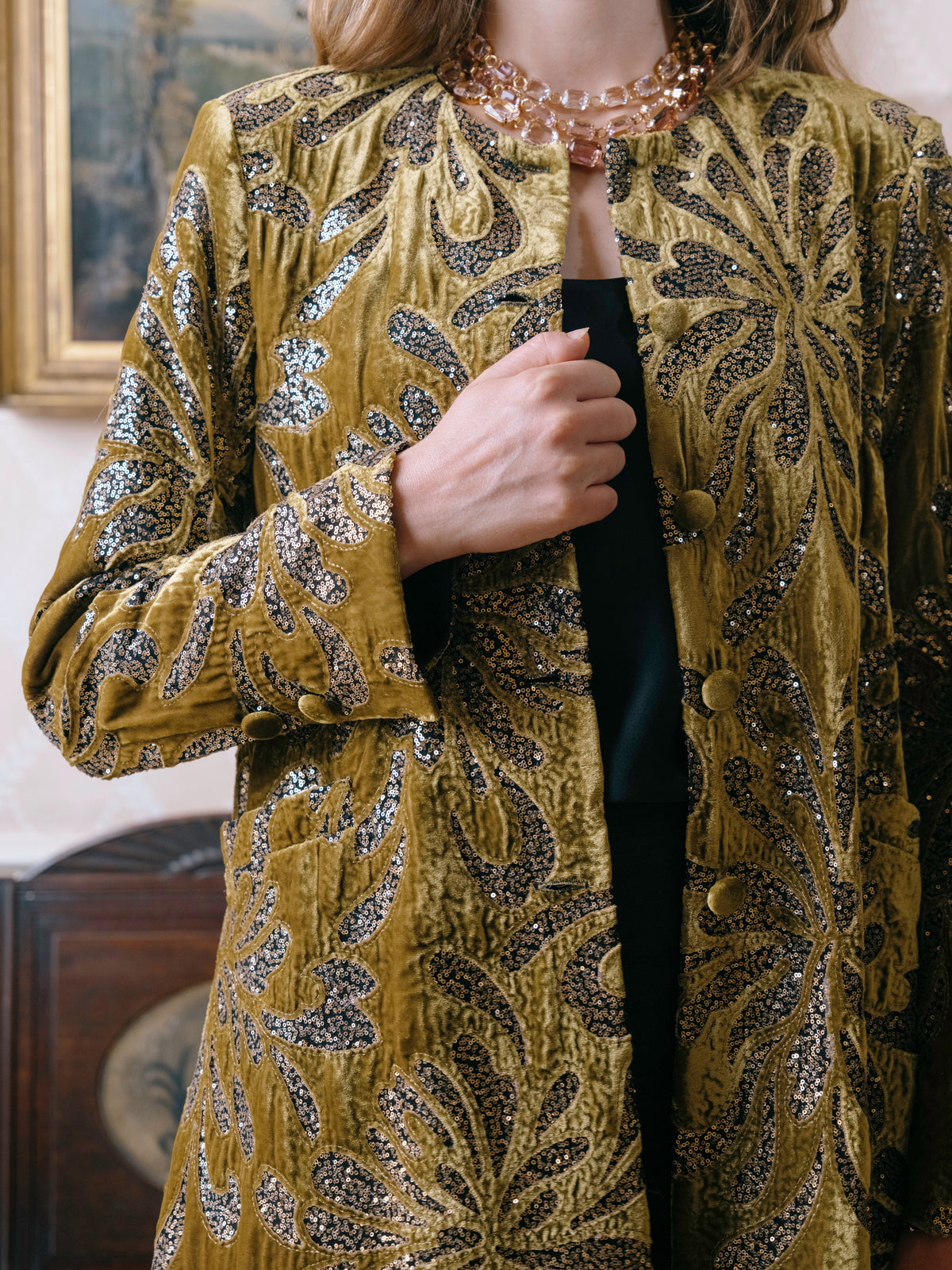 Close detail of an olive brocade coat, showing the weave and beading