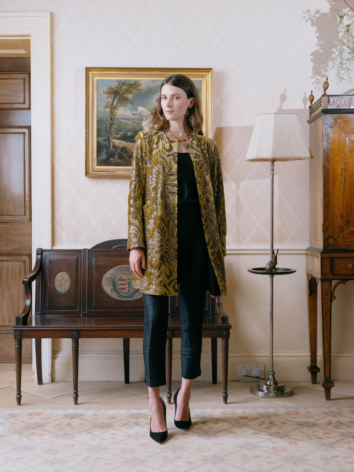An olive brocade coat worn over black, for the evening