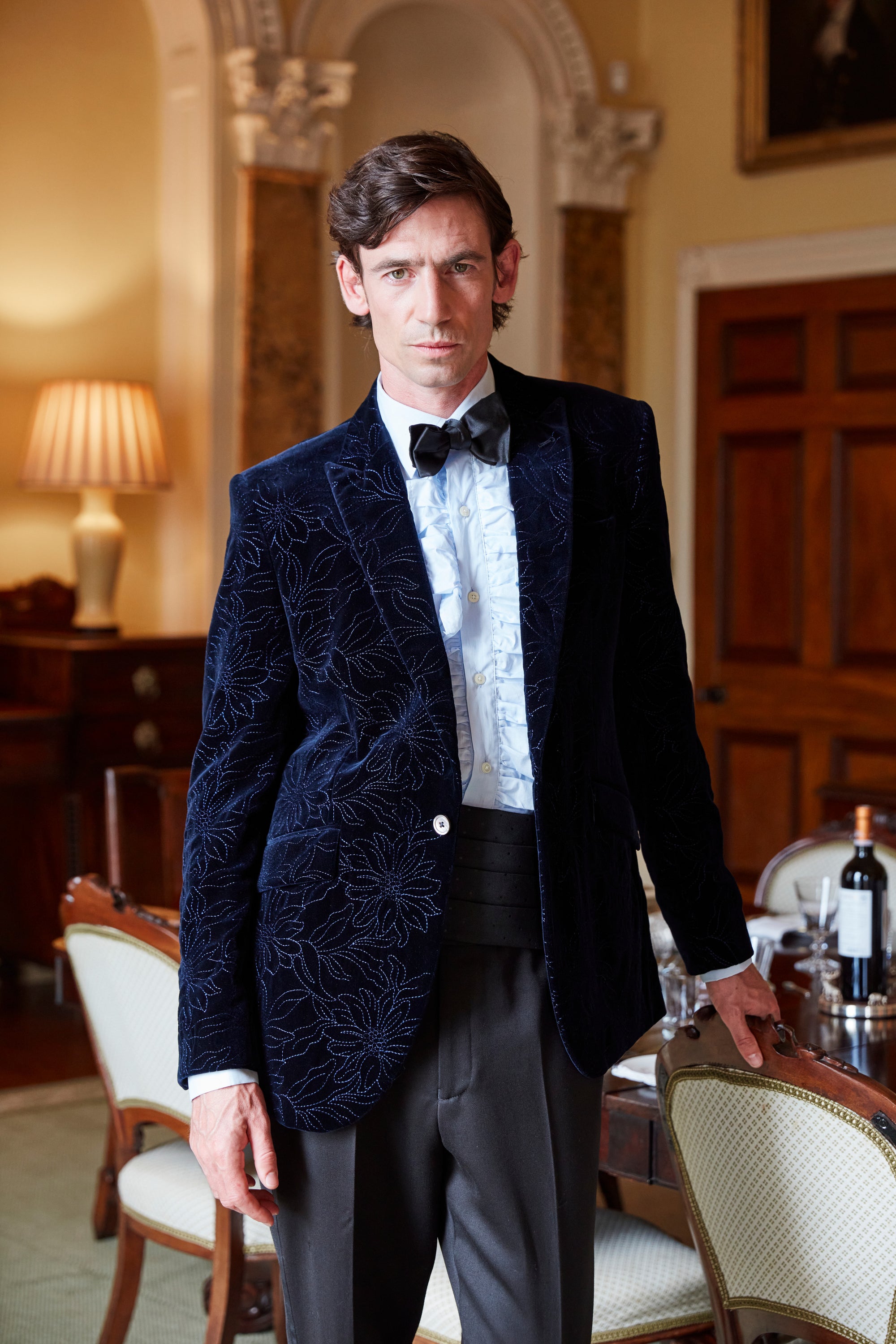 A navy embroidered velvet dinner jacket worn with a black bow tie and cummerbund